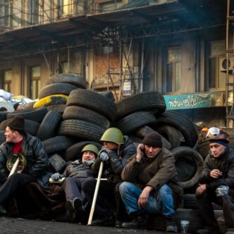Manifestantes sentados junto a barricadas de neumáticos durante los disturbios civiles en Kyiv, Ucrania.