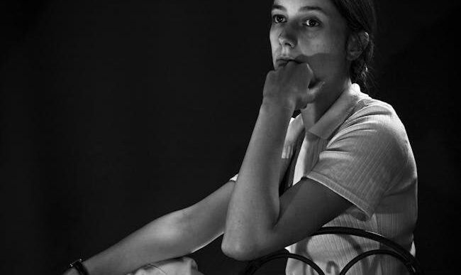 Retrato artístico en blanco y negro que captura a una mujer sumida en sus pensamientos.