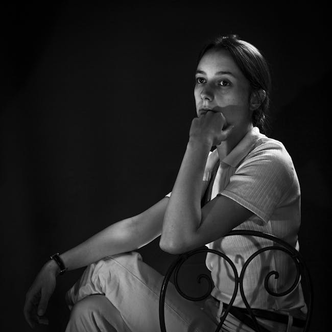 Retrato artístico en blanco y negro que captura a una mujer sumida en sus pensamientos.