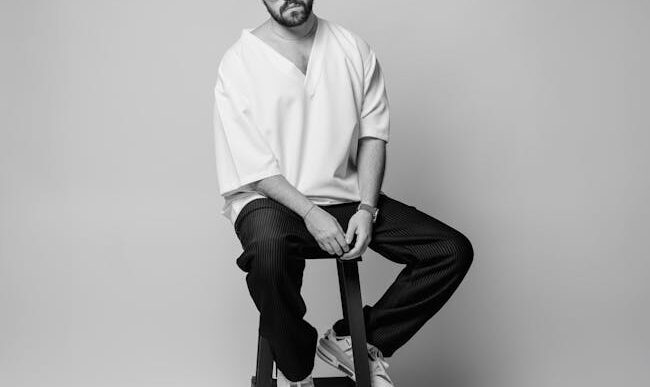 Retrato en blanco y negro de un hombre con gafas de sol, posando elegantemente en un estudio de Teherán.